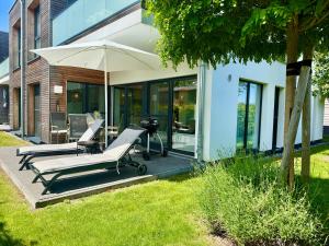 a patio with two lounge chairs and an umbrella at FeWo Lieblingsplatz in Zingst