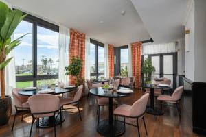 a restaurant with tables and chairs and large windows at Hotel President in Viareggio