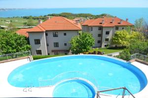 a large blue swimming pool with buildings in the background at Thracian Cliffs Owners Apartments in Kavarna