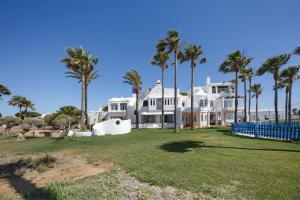 a large white house with palm trees at Finca Isla Verde in Chipiona