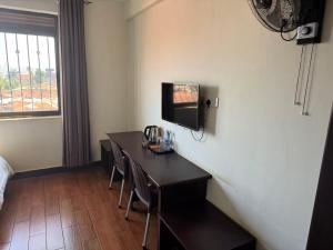 a hotel room with a table and a tv on the wall at Kibuli beijing hotel in Kampala +4 photos