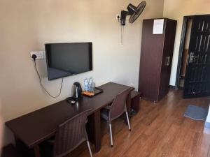 a room with a desk with a television and a table with chairs at Kibuli beijing hotel in Kampala