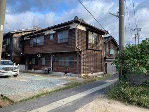 a brick house with a car parked in front of it at GATE80香住 無人宿 完全セルフ 予約メッセージ欄確認要す スマートロック 暗証番号チェックイン 素泊まり専門 アメニティ持参で格安滞在 セコム24h監視 駐車場10台 in Kami