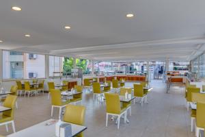 a cafeteria with tables and yellow chairs and tables at Marcan Beach Hotel ADULT ONLY in Oludeniz