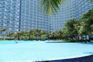 a resort with a pool and palm trees and a building at Arena Oceanview Cam Ranh - Infinity swimming pool in Cam Ranh International Airport