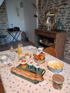 a table with a table cloth with bread and pastries on it at La grange famille in Tournans