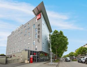 a building with a red sign on the side of it at Ibis Clermont-Ferrand Centre Stade in Clermont-Ferrand