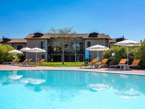 a large swimming pool with chairs and umbrellas at Residence Eden in Peschiera del Garda