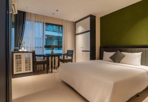 a bedroom with a large white bed and a table at Jolia Nha Trang Hotel in Nha Trang