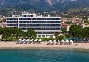 a hotel on the beach with chairs and umbrellas at Airotel Achaia Beach in Patra