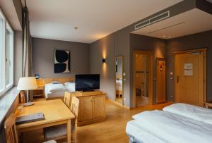 a hotel room with two beds and a desk with a television at Lodenwirt Residence in Vandoies