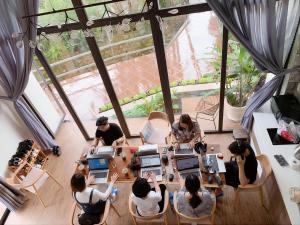 a group of people sitting at a table with laptops at The 1954 House in Da Lat