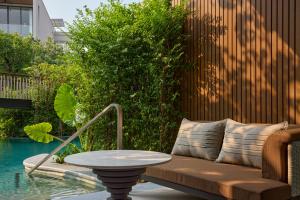 a table and a bench next to a pool at THE BARAI HUA HIN - The Unbound Collection by Hyatt in Hua Hin