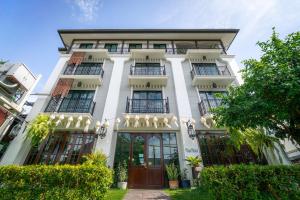 a white building with balconies and trees at Rimwiang in Chiang Mai