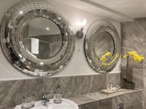 two mirrors on the wall above a sink in a bathroom at Streamside Apartments in Yeovil