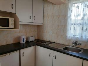 a small kitchen with a sink and a microwave at Phomolo Guest House in Maseru