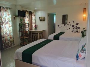 a hotel room with two beds and a desk at The Cronin Residence in Oslob