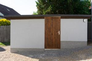 a pair of white garage doors with a wooden door at Apartmán nad pilou in Velké Meziříčí +1 photo