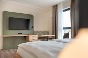 a hotel room with a bed and a flat screen tv at Hotel Neue Mitte in Schlüchtern