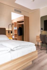 a bedroom with a large white bed and a desk at Hotel Neue Mitte in Schlüchtern