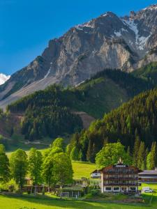 a house in a valley with mountains in the background at Hotel Ramsauhof Zimmer Appartement Pool & Wellness in Ramsau am Dachstein