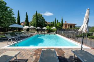 a swimming pool with chairs and umbrellas next to it at Villette di Contignano in Radicofani