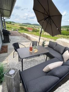 a patio with a couch and a table with an umbrella at Modernes Blockhaus mit Sauna Flair in Lisberg