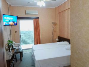 a hotel room with a bed and a flat screen tv at HOTEL ALEXANDROS in Loutraki