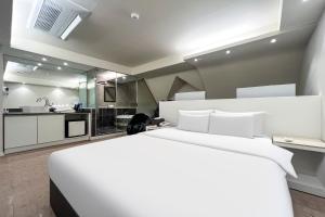 a bedroom with a large white bed and a kitchen at 부평 호텔 루와 in Pup'yŏng-yŏk