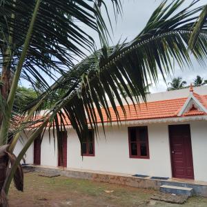 a white house with a red roof and a palm tree at Rooms Varkala Homestay in Varkala