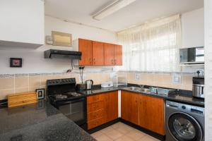 a kitchen with wooden cabinets and a washer at La Ballito 402 in Ballito