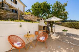 a patio with two chairs and a table with a grill at Casa Outeiro 99 in Paredes de Coura