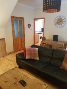 a living room with a black couch and a table at Fisherman Cottage by Langley Serviced Apartments Contractor-Friendly 2BR Stay Sleeps 4 Free WiFi Free Parking 20 Minutes to Banniskirk in Wick +3 photos