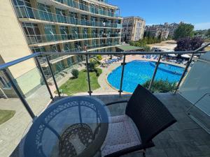 a balcony with a table and chairs and a swimming pool at Turtle Apartment Sunny Beach in Sunny Beach