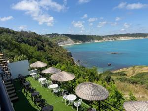 a row of chairs and umbrellas on a lawn with a beach at Marina Boutique Hotel Istanbul Airport in Karaburun