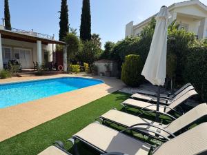 a group of chairs and an umbrella next to a swimming pool at Beach Villa Sofia in Neo Chorio