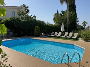 a swimming pool with chairs and a house at Beach Villa Sofia in Neo Chorio
