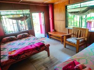 a bedroom with two beds and a bench and windows at Hillside Highway Cottages in Shillong