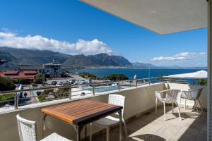 een balkon met een tafel en stoelen en uitzicht op het water bij Harbour House Hotel - Harbour Square in Hermanus
