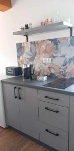 a kitchen counter with a flower mural on the wall at Domek Pod Strzegominą in Szerzyny