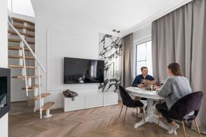 a man and woman sitting at a table in a living room at Tesoro Dolce Vita Apartment in Pogórze