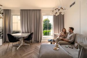 a man and woman sitting on a couch in a living room at Tesoro Dolce Vita Apartment in Pogórze