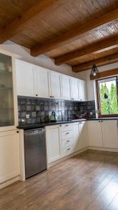 a large kitchen with white cabinets and a window at Zacisze nad Orlicą in Międzylesie