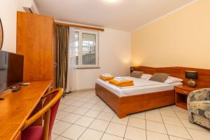 a bedroom with a bed and a desk and a television at Guesthouse Villa Adria in Malinska