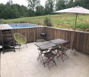 a patio with a table and chairs and an umbrella at A 5 min de Lascaux - Ferme Périgourdine - Gîte du Fraysse in Montignac
