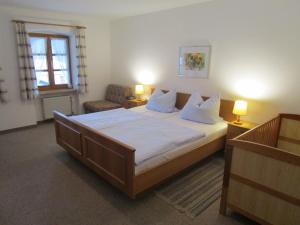 a bedroom with a large bed and a chair at Schneiderhof in Rimsting