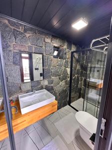 a stone bathroom with a sink and a shower at Novella Bungalov in Işıklı