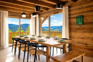 a dining room with a table and chairs and windows at Chalet Le Cocon des Marmottes Vue Imprenable Confort Haut de Gamme & Services sur Mesure in Gérardmer
