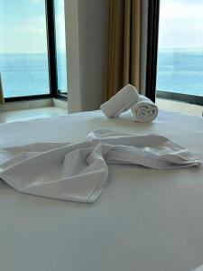 a white bed with towels on it in front of a window at Borsh sunset apartments in Borsh