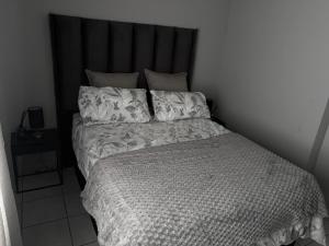 a bedroom with a bed with a black headboard and pillows at Malwandla 1bed full apartment in Centurion